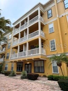 A multi-story yellow apartment building features stacked balconies with white railings and a paved courtyard — 860 N ORANGE AVENUE UNIT 146, ORLANDO, FL