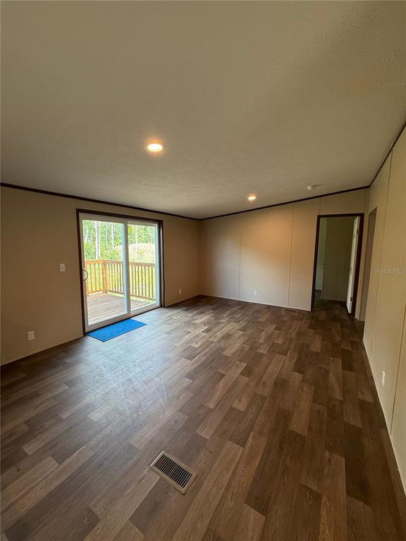 An empty room features wood-look flooring, recessed lighting, a sliding glass door, and a floor vent — 4246 LA SALLE AVENUE, ST CLOUD, FL