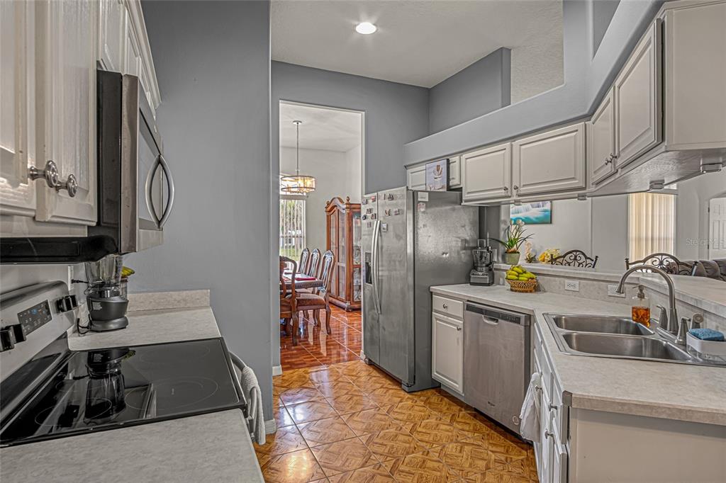 A kitchen with white cabinets, stainless steel appliances, and brown patterned tile flooring — 525 JUSTINE AVENUE NW, PALM BAY, FL