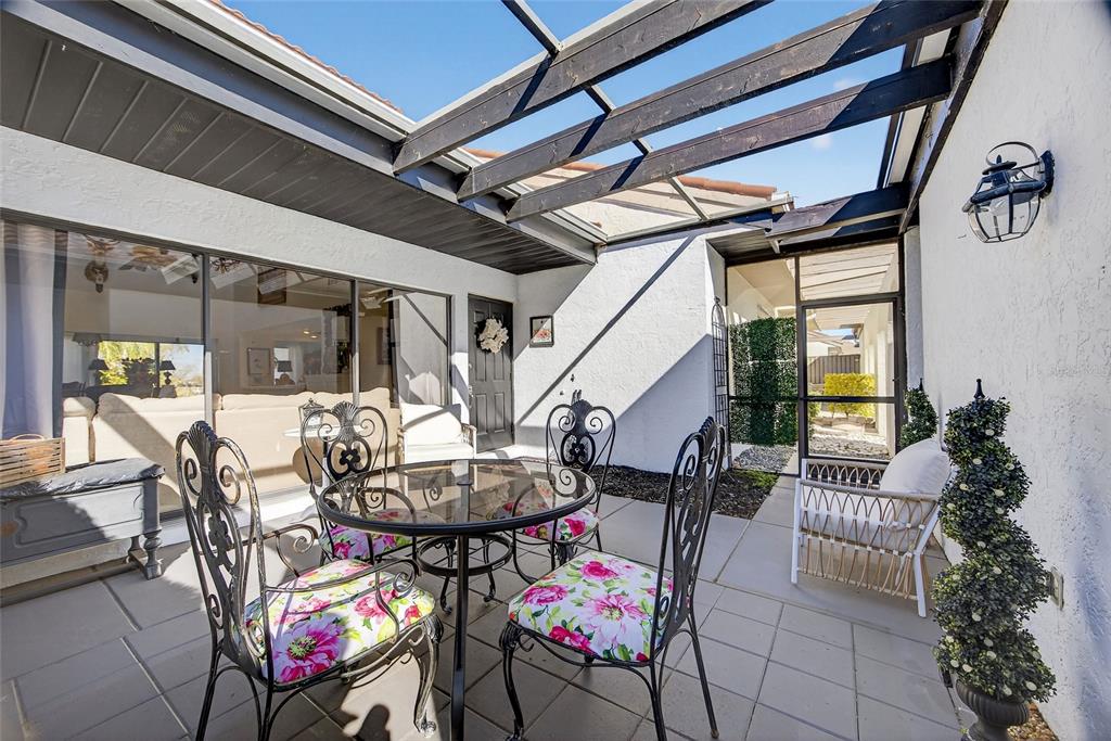 A patio with a glass-topped table, four chairs, and a screen enclosure — 5061 SAN ROCCO COURT, PUNTA GORDA, FL
