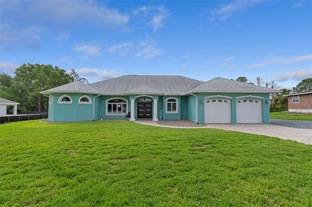 A teal-colored single-story house with a two-car garage and a large front lawn — 5050 FREEPORT DRIVE, SPRING HILL, FL