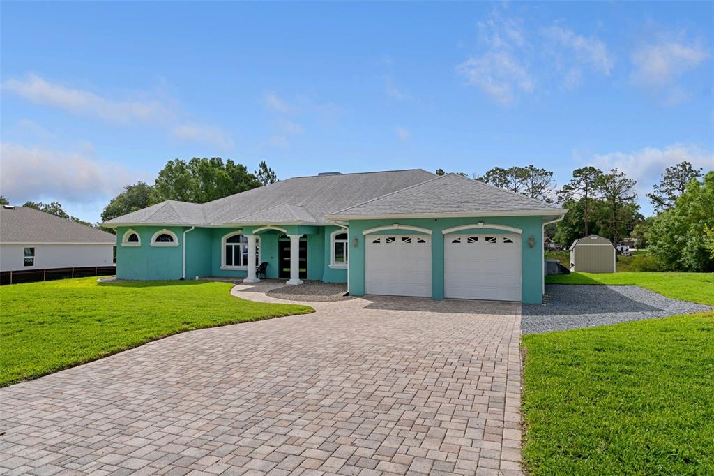 A teal single-story house features a two-car garage and a paved driveway — 5050 FREEPORT DRIVE, SPRING HILL, FL