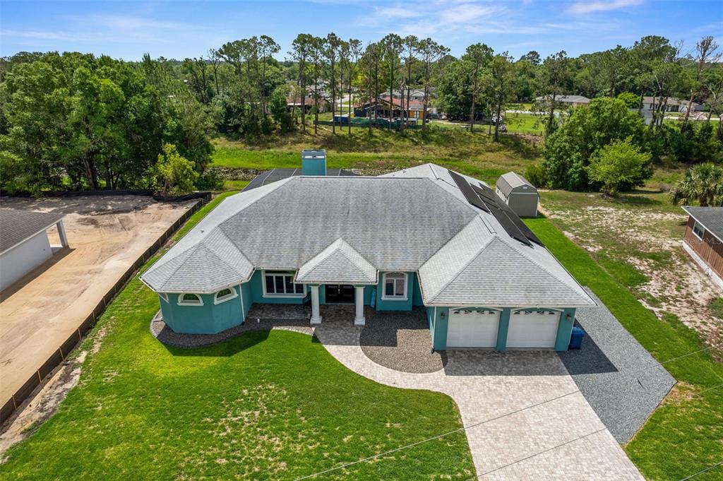 An aerial view shows a teal single-story house with a gray roof and paved driveway — 5050 FREEPORT DRIVE, SPRING HILL, FL