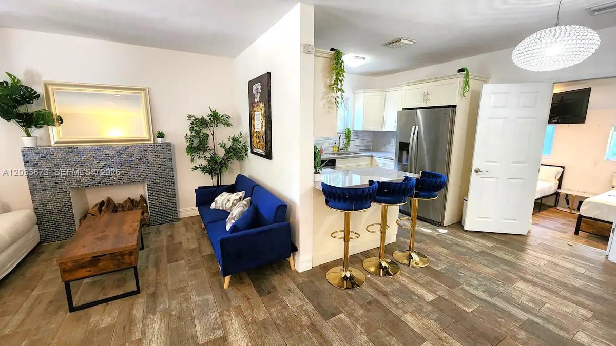 A living room with a blue sofa and fireplace opens into a kitchen with stools — 11 NW 47th Ter, Miami FL 33127, MIAMI, FL