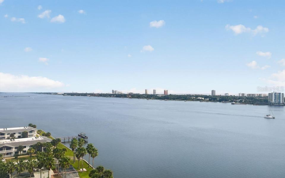 An elevated view of a wide river with a shoreline featuring buildings and palm trees — 241 RIVERSIDE DRIVE UNIT 1204, HOLLY HILL, FL