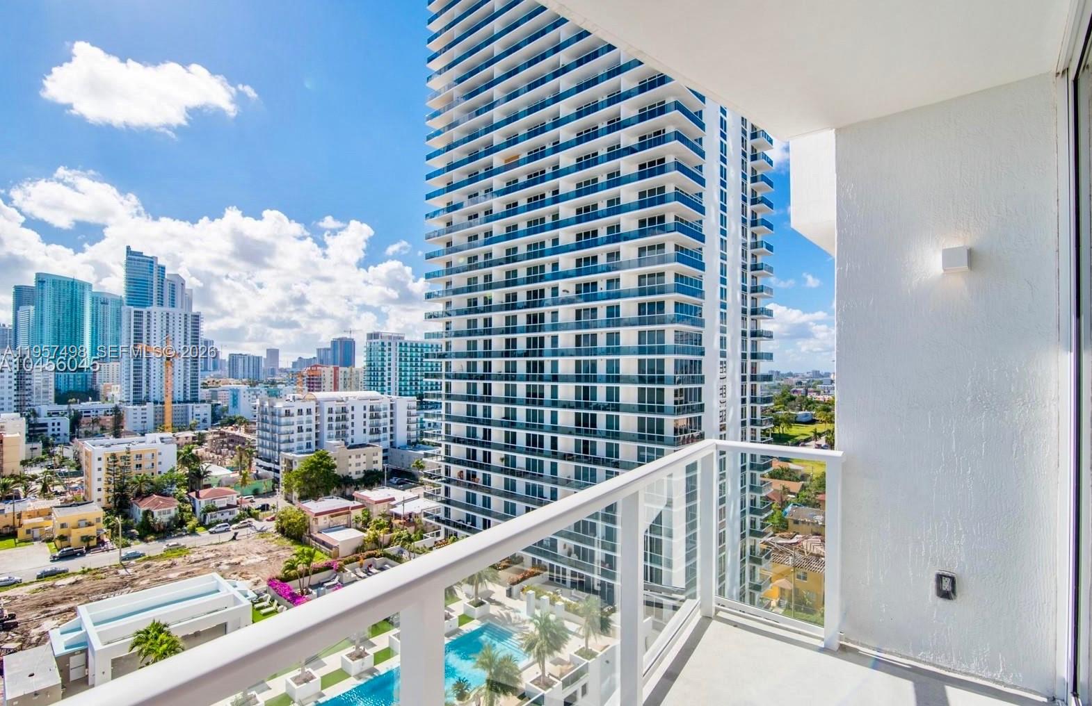 A balcony view overlooks a swimming pool and a tall residential skyscraper in a city — 601 NE 27TH ST # 1706, Miami FL 33137, MIAMI, FL