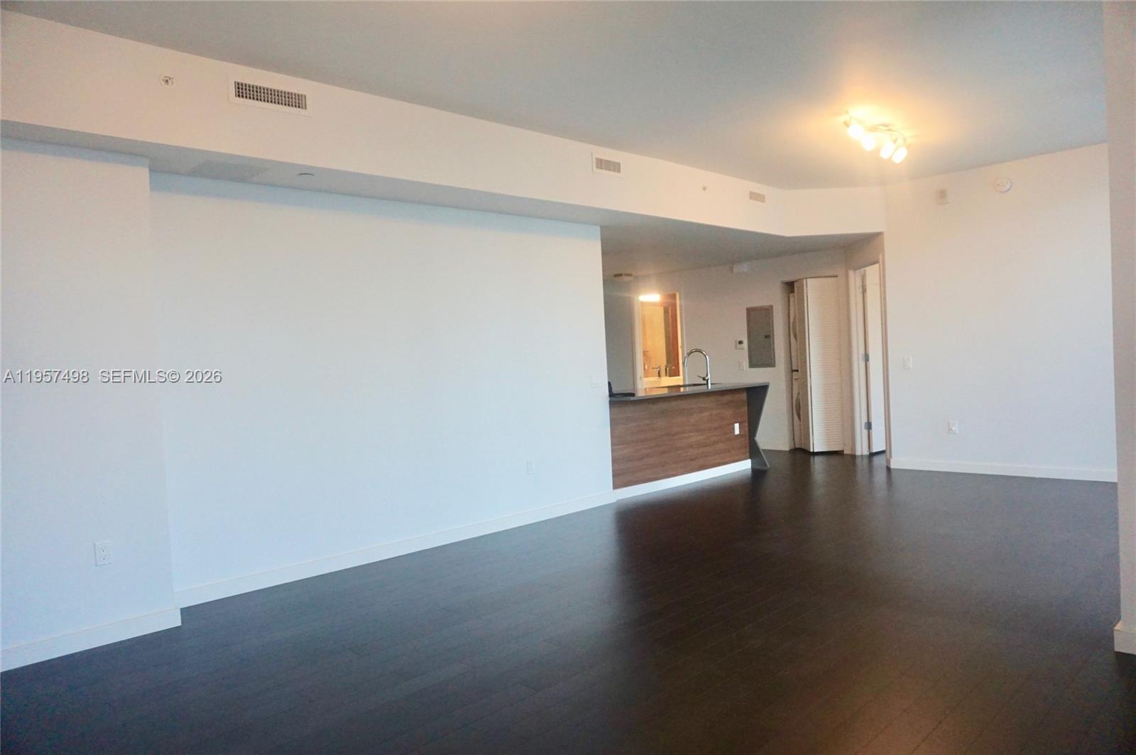 An open-concept living area features dark wood flooring, white walls, and a kitchen island — 601 NE 27TH ST # 1706, Miami FL 33137, MIAMI, FL