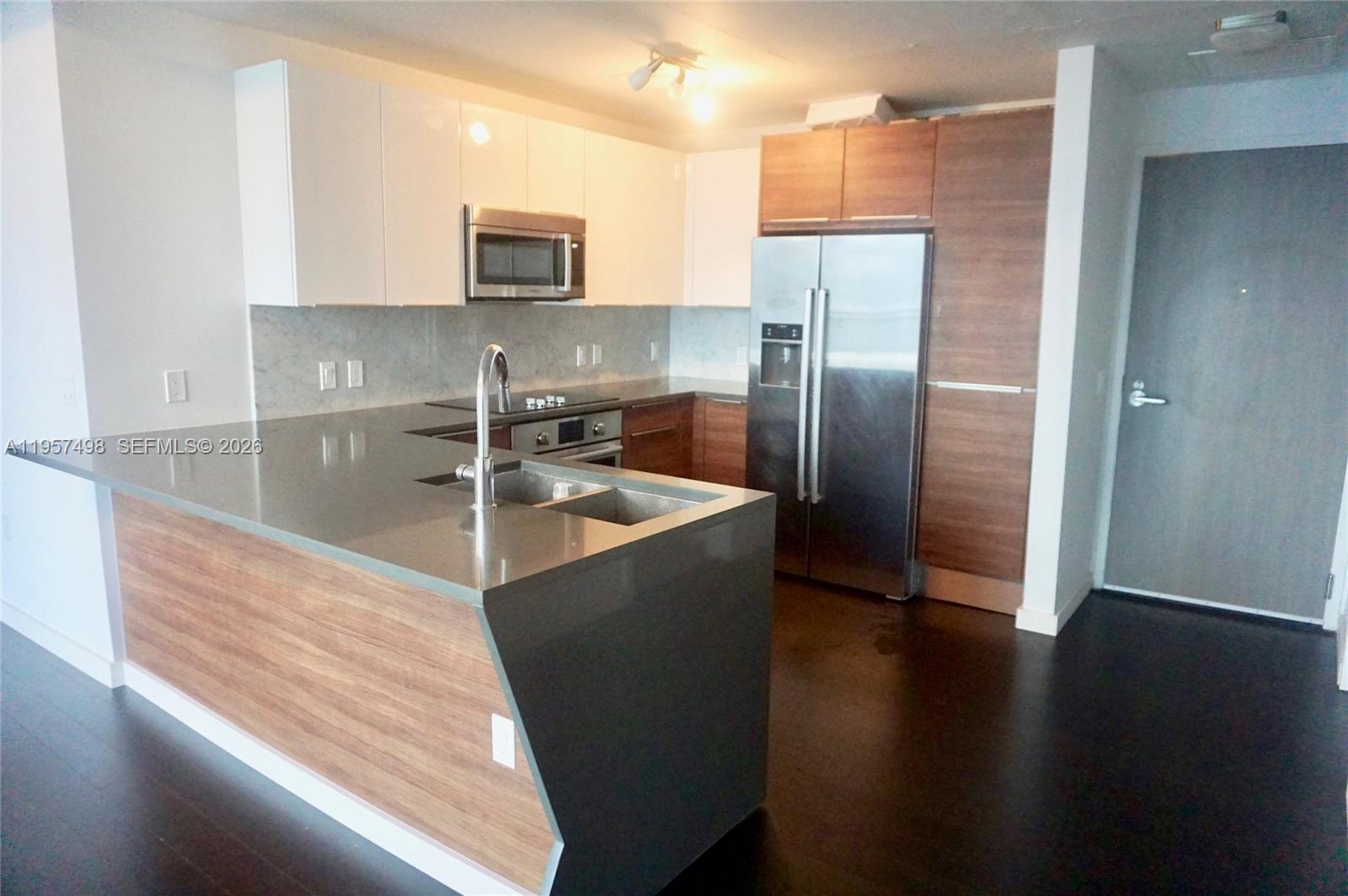 A modern kitchen features two-toned wood and white cabinetry, stainless steel appliances, and gray countertops — 601 NE 27TH ST # 1706, Miami FL 33137, MIAMI, FL