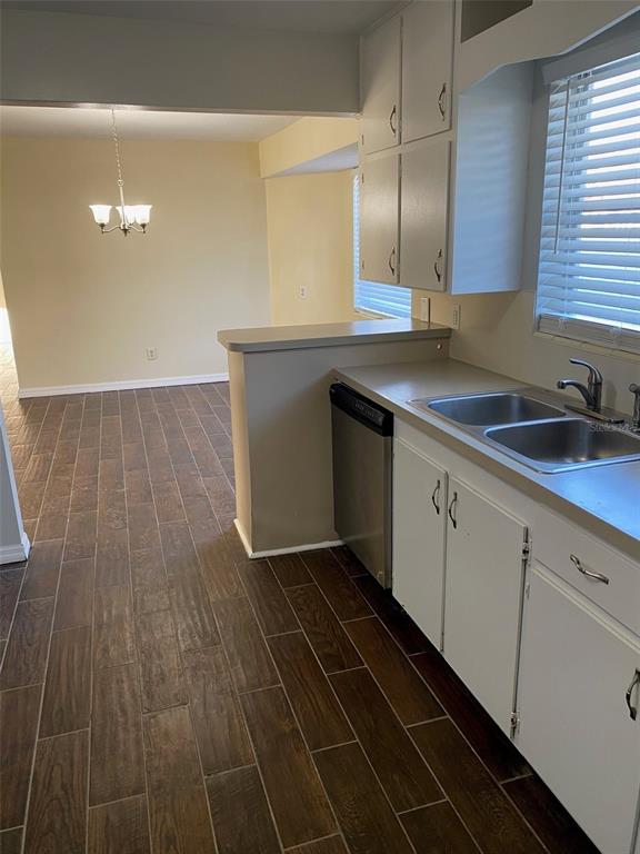 A kitchen with white cabinets, a stainless steel dishwasher, and wood-look tile flooring — 803 HASELTON STREET, EUSTIS, FL