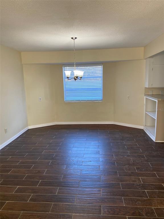 An empty dining area features dark wood-look tile flooring, a chandelier, and a bay window — 803 HASELTON STREET, EUSTIS, FL