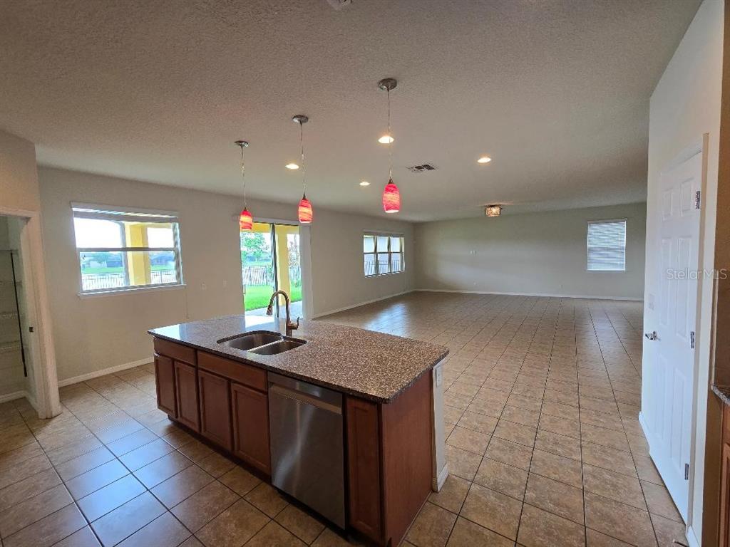 A kitchen with wood cabinets, granite countertops, a center island, and tiled flooring — 2610 MEAD AVENUE, ST CLOUD, FL
