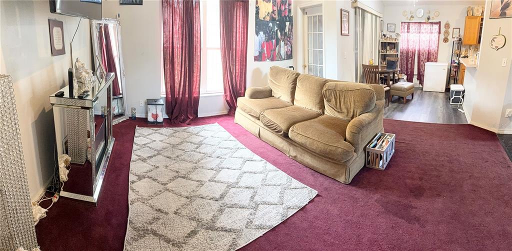 A living room features a tan sofa, a patterned area rug, and deep red carpeting — 7031 BLAIR DRIVE, ORLANDO, FL