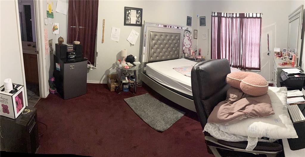 A bedroom features a tufted headboard, dark red carpeting, and a desk with a chair — 7031 BLAIR DRIVE, ORLANDO, FL