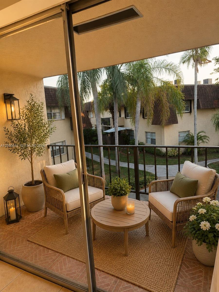 A balcony features two wicker chairs, a round table, and potted plants overlooking a courtyard — 9108 SW 137th Ter # 3, Miami FL 33176, MIAMI, FL