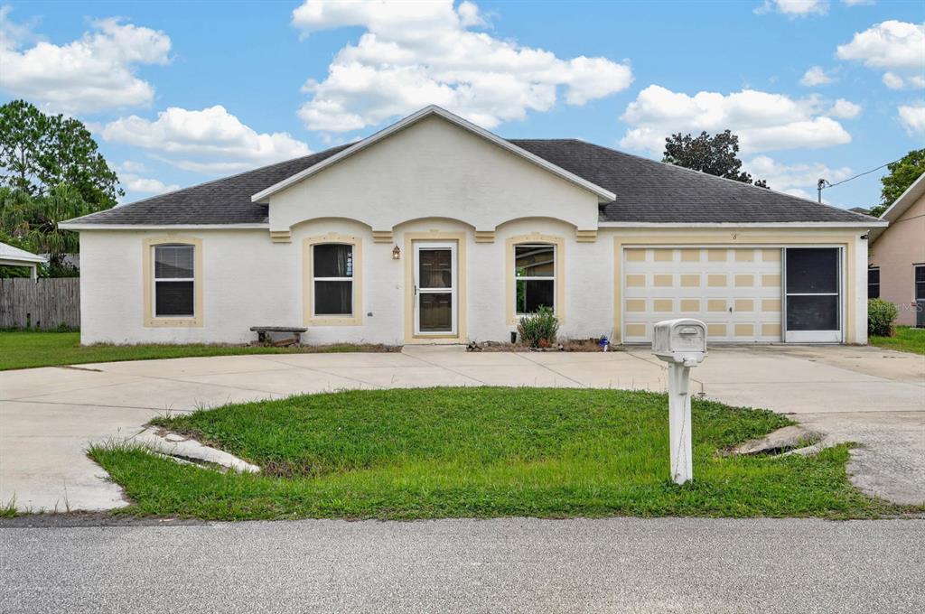 A single-story white house with a concrete driveway, a two-car garage, and a front lawn — 6 BROWNSTONE LANE, PALM COAST, FL