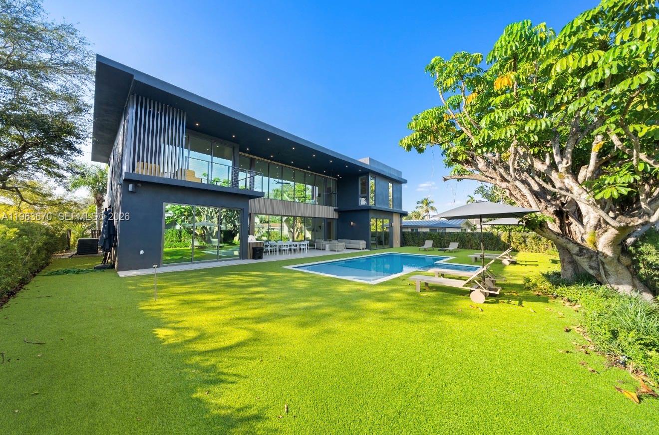 A modern two-story house with a flat roof overlooks a swimming pool and green lawn — 19701 NE 21st Ct, Miami FL 33179, MIAMI, FL
