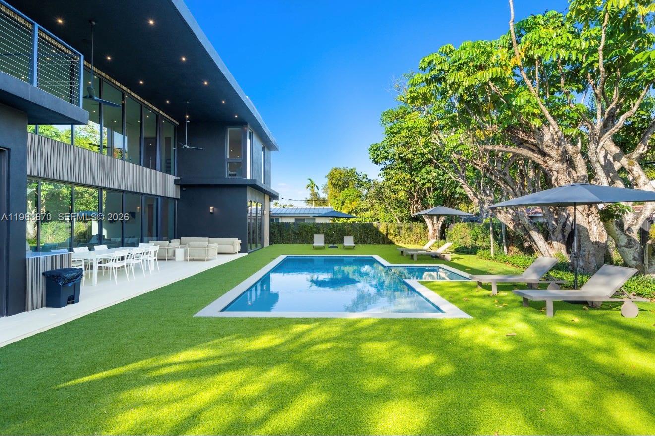 A modern dark-gray house features a backyard with a swimming pool and artificial turf — 19701 NE 21st Ct, Miami FL 33179, MIAMI, FL