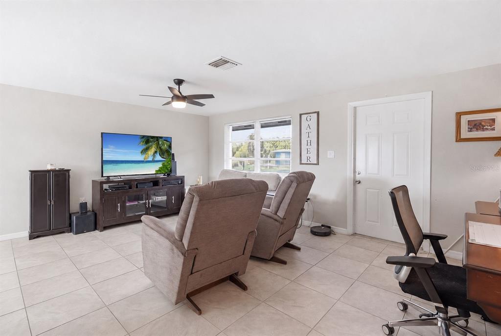A living room features tile flooring, two recliners, a television console, and a desk area — 3178 SUNRISE TRAIL, PORT CHARLOTTE, FL