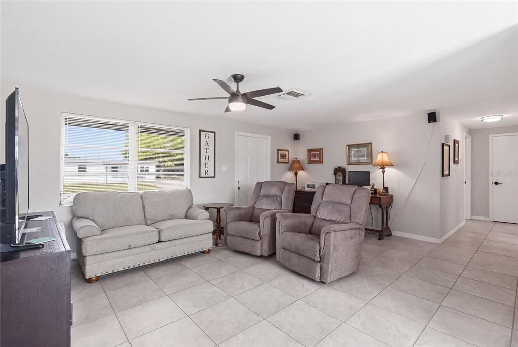 A living room features light gray tile flooring, a sofa, two recliners, and a ceiling fan — 3178 SUNRISE TRAIL, PORT CHARLOTTE, FL