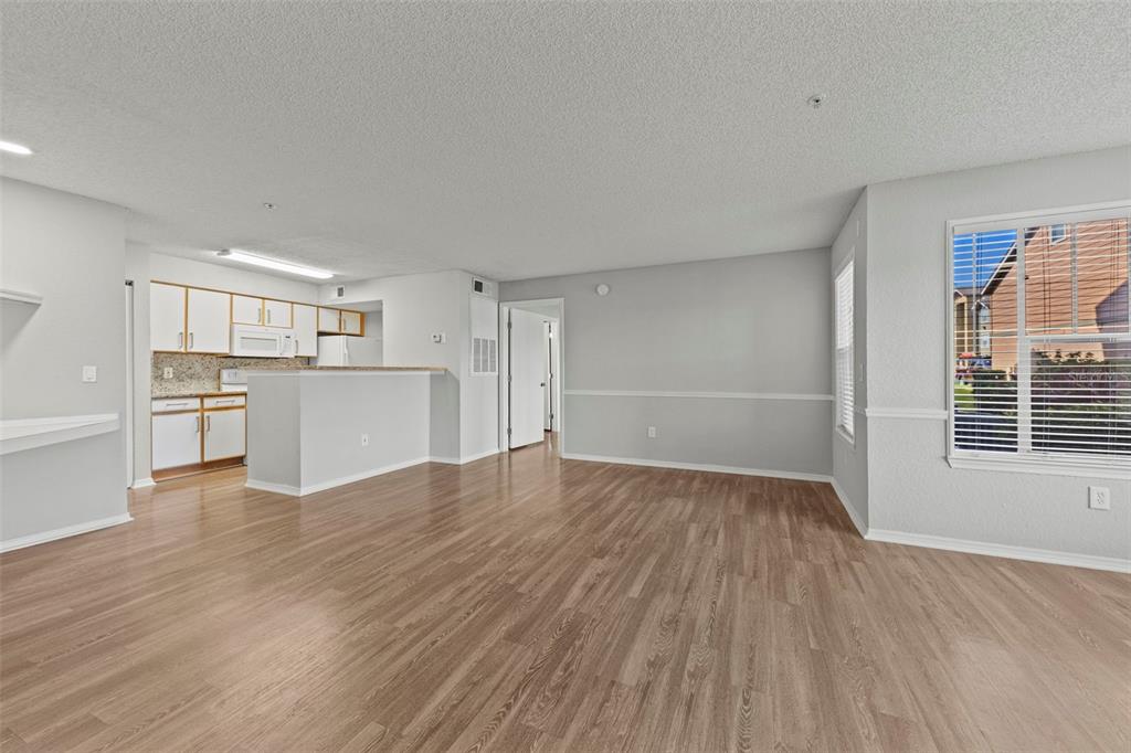 An open-concept living area with wood-look flooring and a kitchen featuring white cabinets — 2212 GRAND CAYMAN COURT UNIT 1616, KISSIMMEE, FL