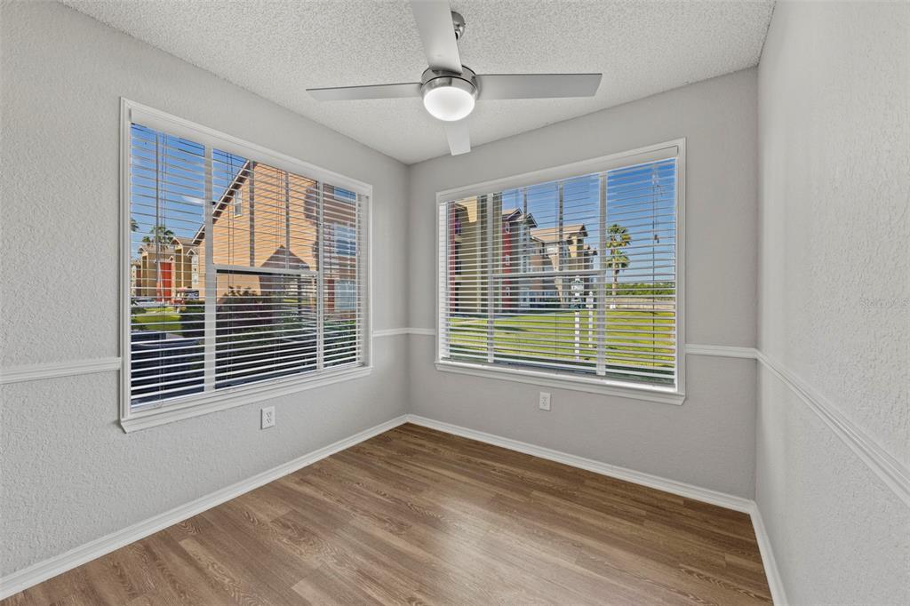 An empty room with light gray walls, wood-look flooring, a ceiling fan, and two windows — 2212 GRAND CAYMAN COURT UNIT 1616, KISSIMMEE, FL