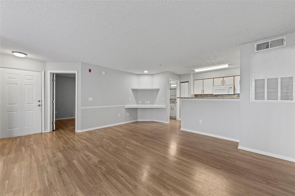 An open-concept living area with light gray walls, wood-look flooring, and a kitchen breakfast bar — 2212 GRAND CAYMAN COURT UNIT 1616, KISSIMMEE, FL