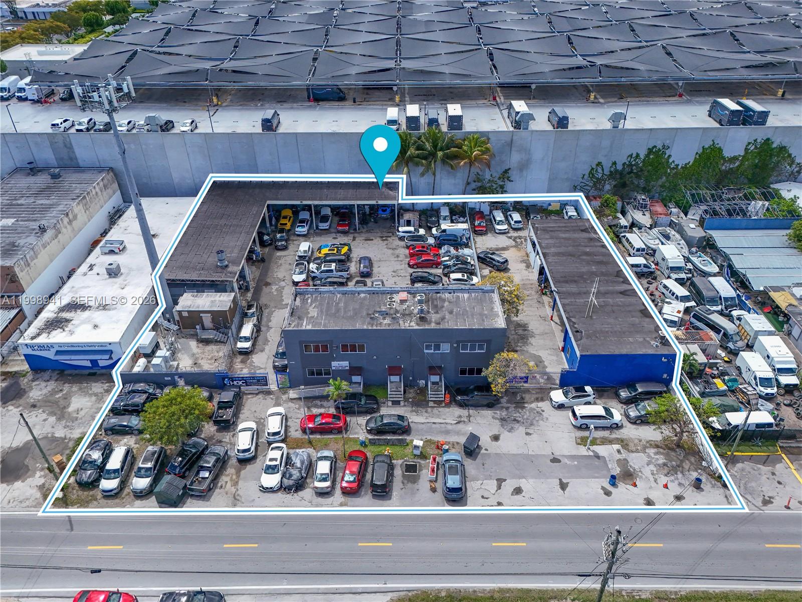 This aerial view shows a commercial property with a central building and surrounding parking lot — 3326 NW South River Dr, Miami FL 33142, MIAMI, FL