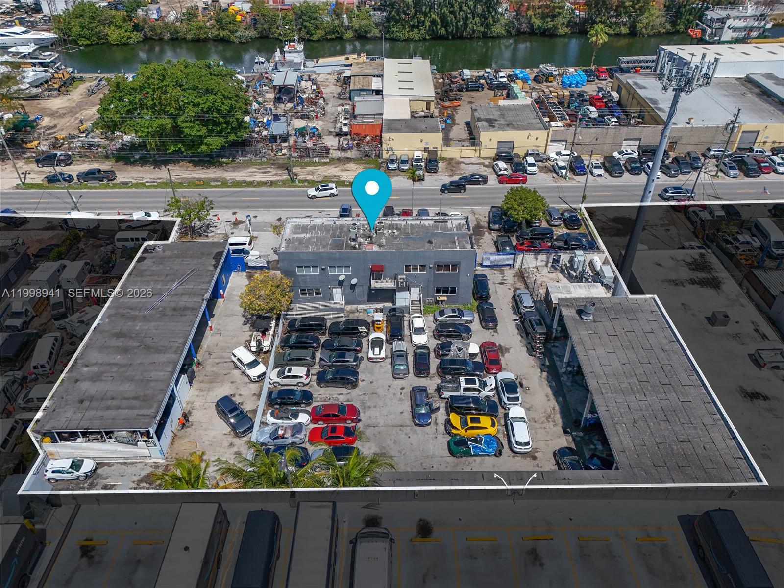 An aerial view shows a commercial building with a parking lot filled with cars — 3326 NW South River Dr, Miami FL 33142, MIAMI, FL
