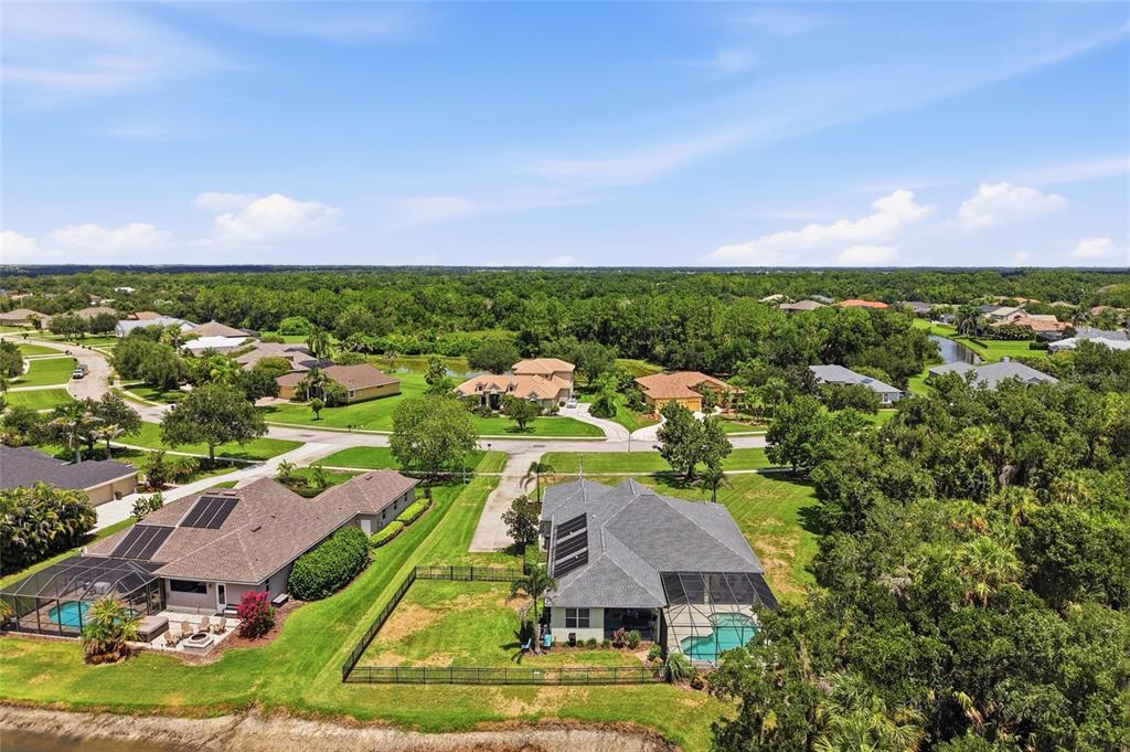 An aerial view shows two suburban houses with swimming pools and fenced backyards near trees — 15449 MULHOLLAND ROAD, PARRISH, FL