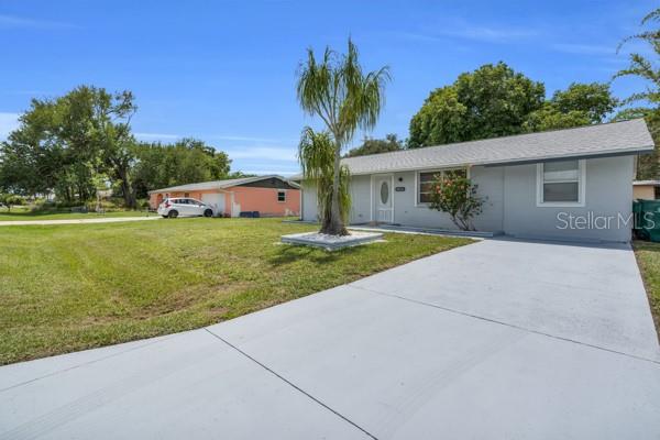 A light gray house with a palm tree in the front yard and a driveway — 18634 GOODMAN CIRCLE, PORT CHARLOTTE, FL
