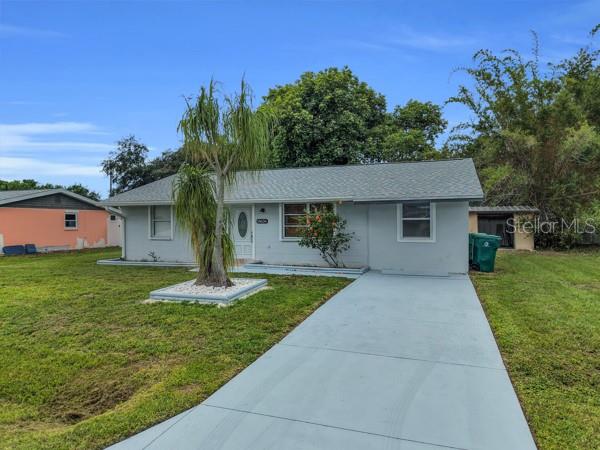 A single-story house with a gray exterior, a paved driveway, and a palm tree — 18634 GOODMAN CIRCLE, PORT CHARLOTTE, FL
