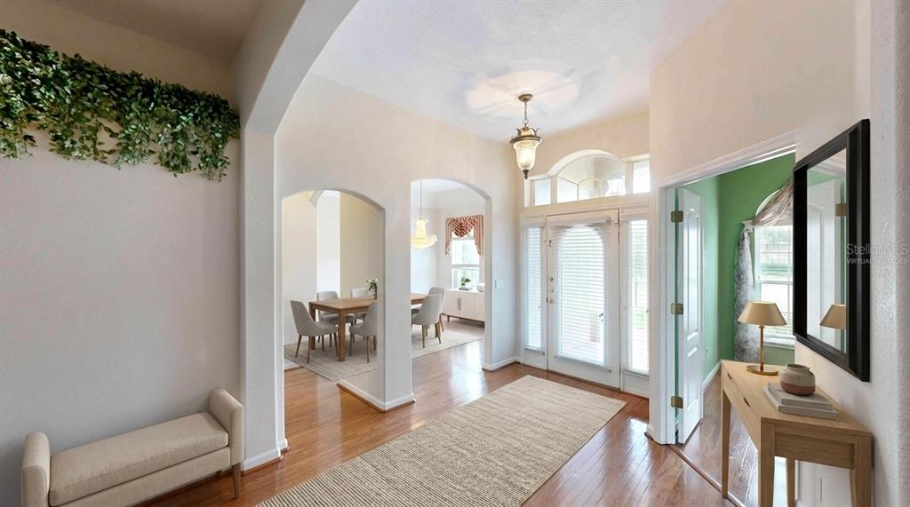 A bright entryway features hardwood floors, an arched doorway to a dining room, and furniture — 529 BELHAVEN FALLS DRIVE, OCOEE, FL