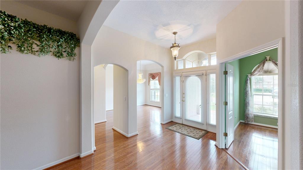 A bright foyer features hardwood floors, arched entryways, and a front door with sidelights — 529 BELHAVEN FALLS DRIVE, OCOEE, FL