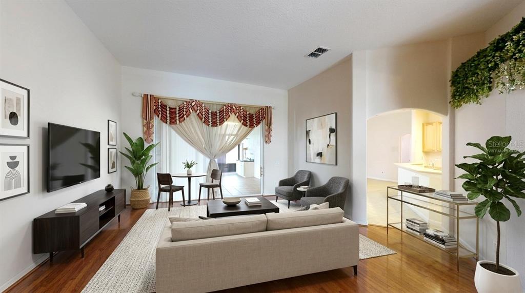 A living room features a sofa, television, two armchairs, a dining area, and hardwood floors — 529 BELHAVEN FALLS DRIVE, OCOEE, FL