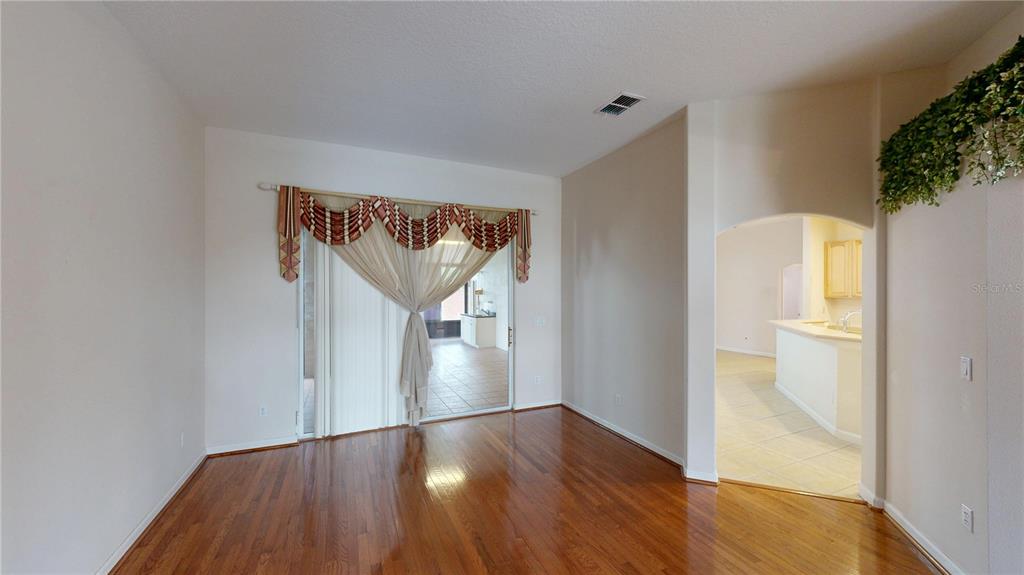 A living room with hardwood floors, a sliding glass door, and an arched entryway — 529 BELHAVEN FALLS DRIVE, OCOEE, FL