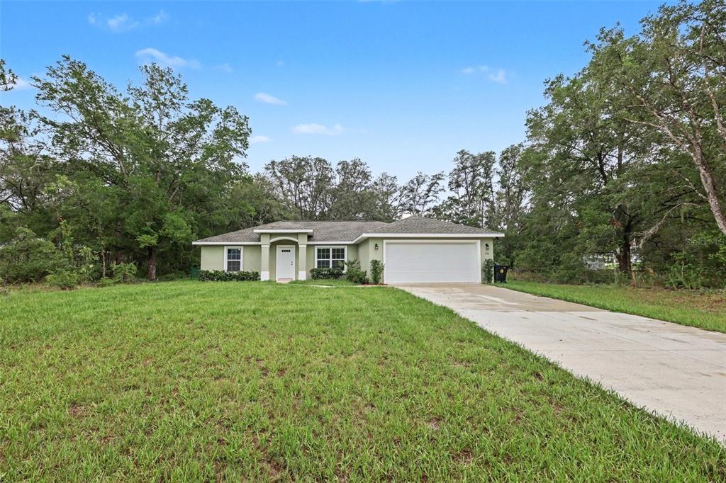 A single-story house with a light green exterior, a two-car garage, and a concrete driveway — 280 W BRIMSON PLACE, CITRUS SPRINGS, FL