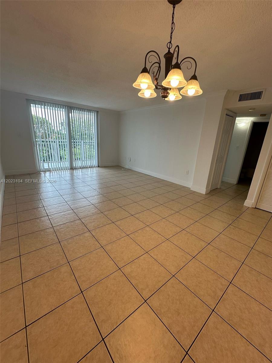 This room features light-colored tile flooring, a decorative chandelier, and sliding glass balcony doors — 6930 Miami Gardens Dr # 408, Hialeah FL 33015, HIALEAH, FL