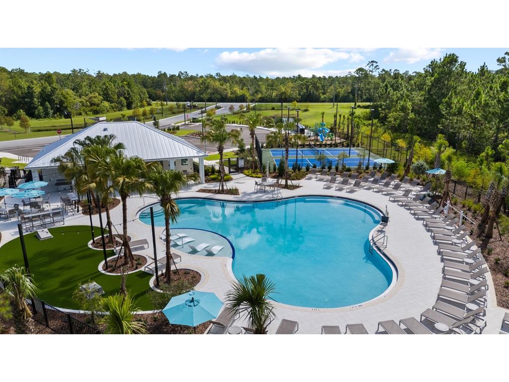 An aerial view of a community pool area with lounge chairs, palm trees, and courts — 22 GARNI DRIVE, PALM COAST, FL