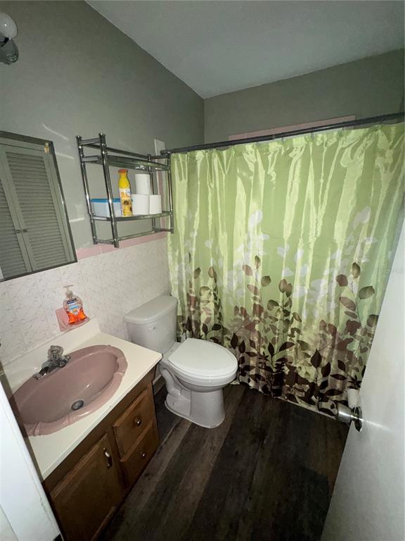 A bathroom features a pink sink, a white toilet, and a green patterned shower curtain — 3845 40TH AVENUE N, ST PETERSBURG, FL