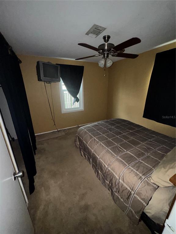 A bedroom features a bed with a plaid comforter, a ceiling fan, and a wall-mounted television — 3845 40TH AVENUE N, ST PETERSBURG, FL