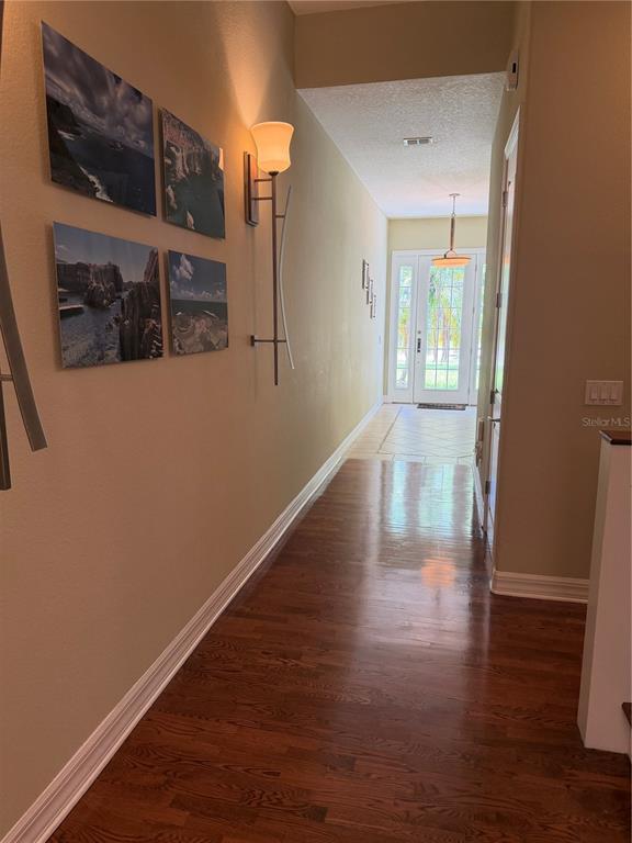 A hallway with hardwood floors, wall art, and a sconce leading to a glass-paneled door — 1009 ELMWOOD STREET UNIT 1009, ORLANDO, FL