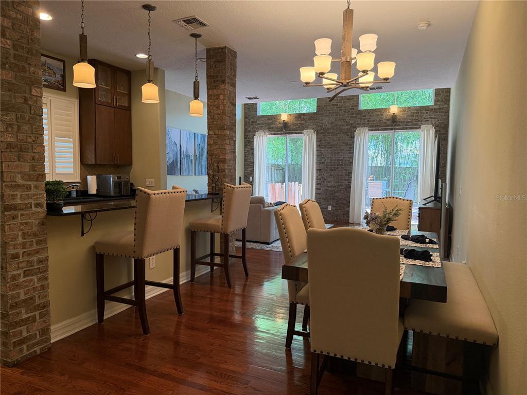 A dining area and kitchen breakfast bar feature brick columns, hardwood floors, and pendant lighting — 1009 ELMWOOD STREET UNIT 1009, ORLANDO, FL