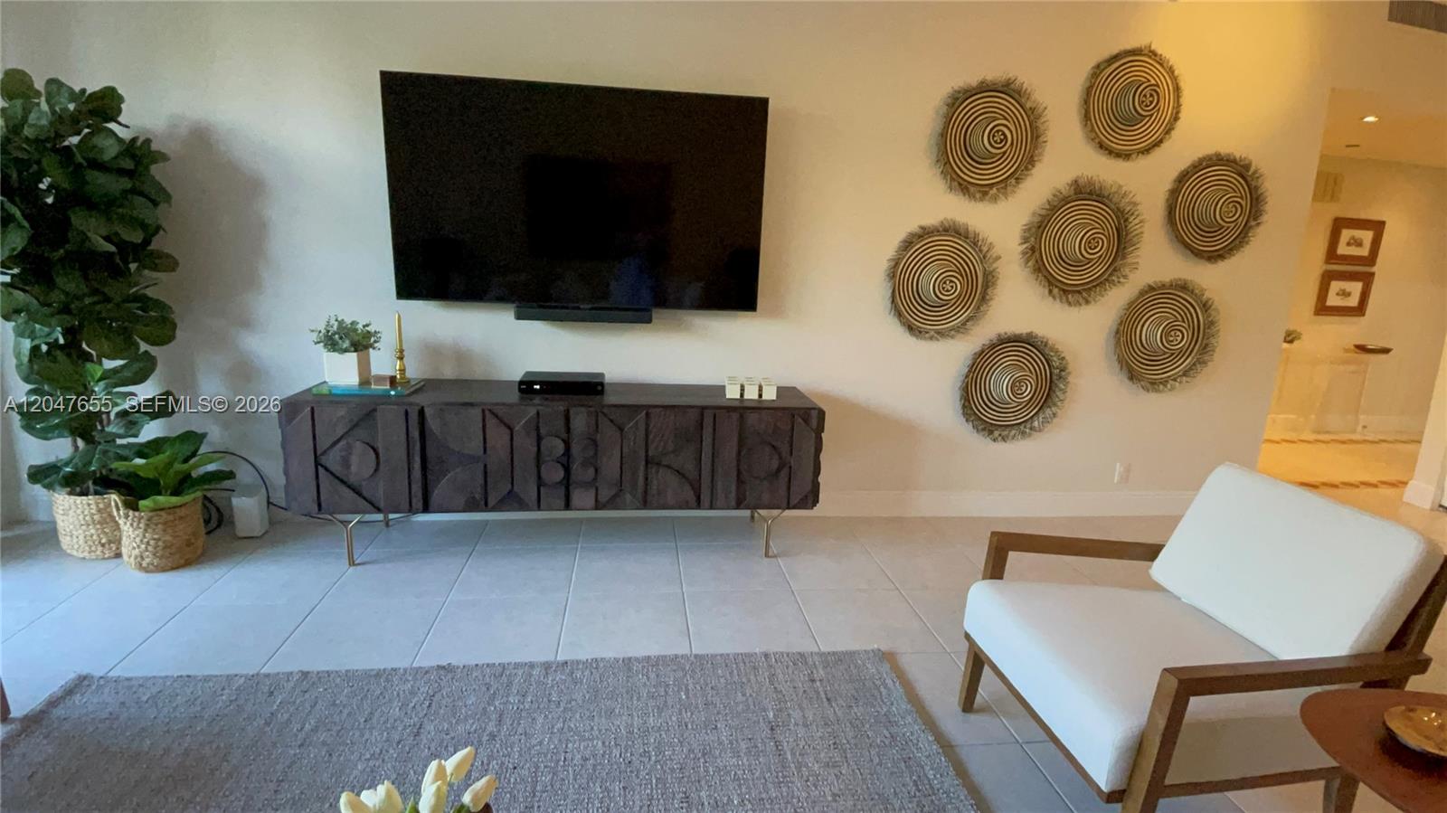 A living room features a wall-mounted television, a dark wooden console, and decorative wall baskets — 151 Crandon Blvd # 236, Key Biscayne FL 33149, KEY BISCAYNE, FL