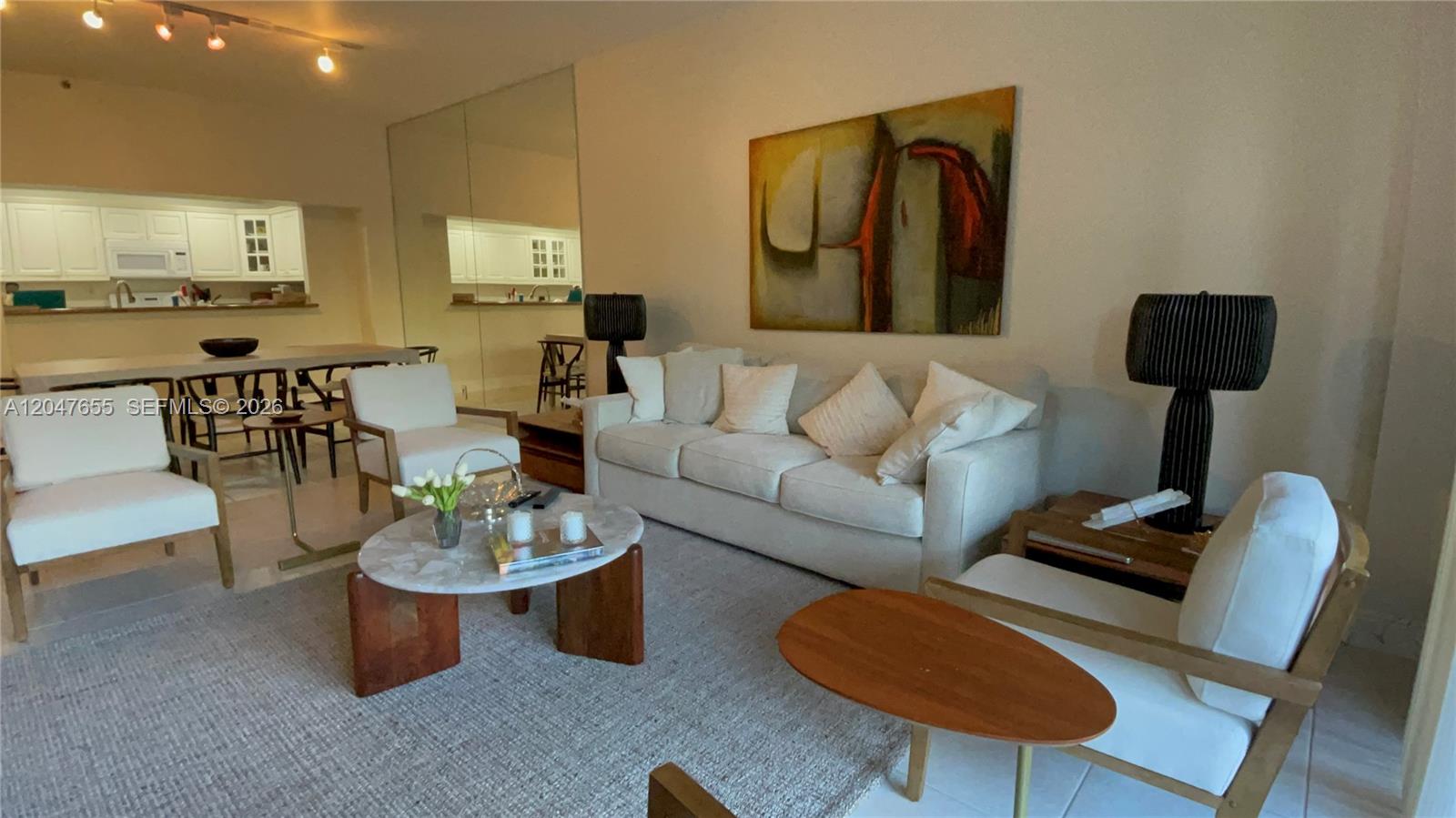 A living room features a white sofa, armchairs, a marble coffee table, and abstract art — 151 Crandon Blvd # 236, Key Biscayne FL 33149, KEY BISCAYNE, FL