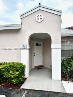 A light-colored stucco house features an arched entryway with a white front door — 1542 Springside Dr # 1542, Weston FL 33326, WESTON, FL