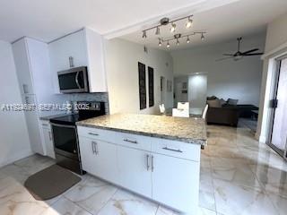 A kitchen with white cabinets, granite countertops, and stainless steel appliances opens to a living area — 1542 Springside Dr # 1542, Weston FL 33326, WESTON, FL