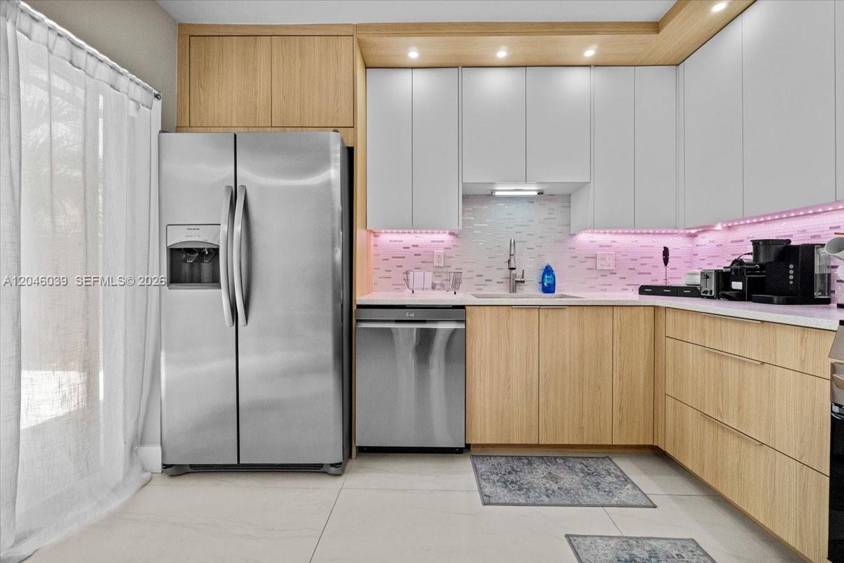 A modern kitchen features stainless steel appliances, light wood cabinetry, and pink under-cabinet lighting — 2891 SW 11th Pl, Deerfield Beach FL 33442, DEERFIELD BEACH, FL