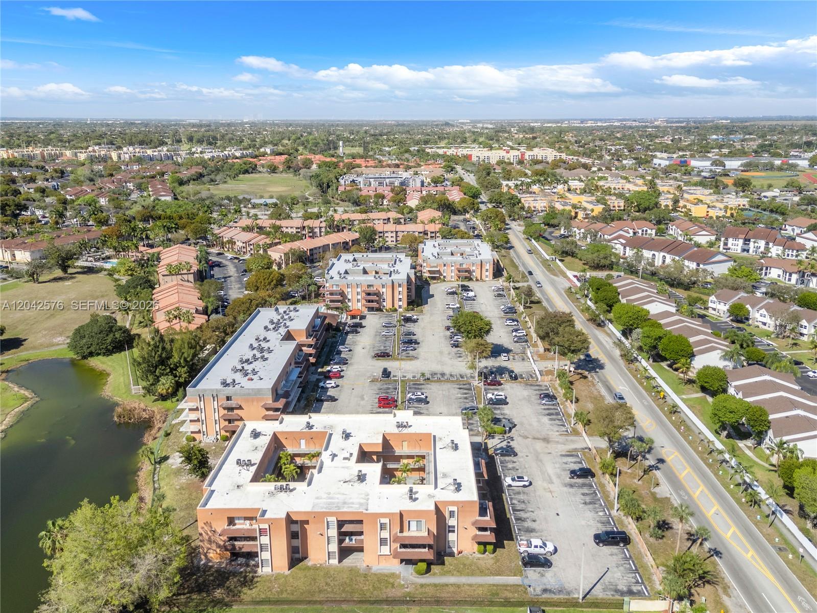 An aerial view shows multi-story apartment buildings with parking lots and a nearby pond — 17530 NW 68th Ave # C2003, Hialeah FL 33015, HIALEAH, FL