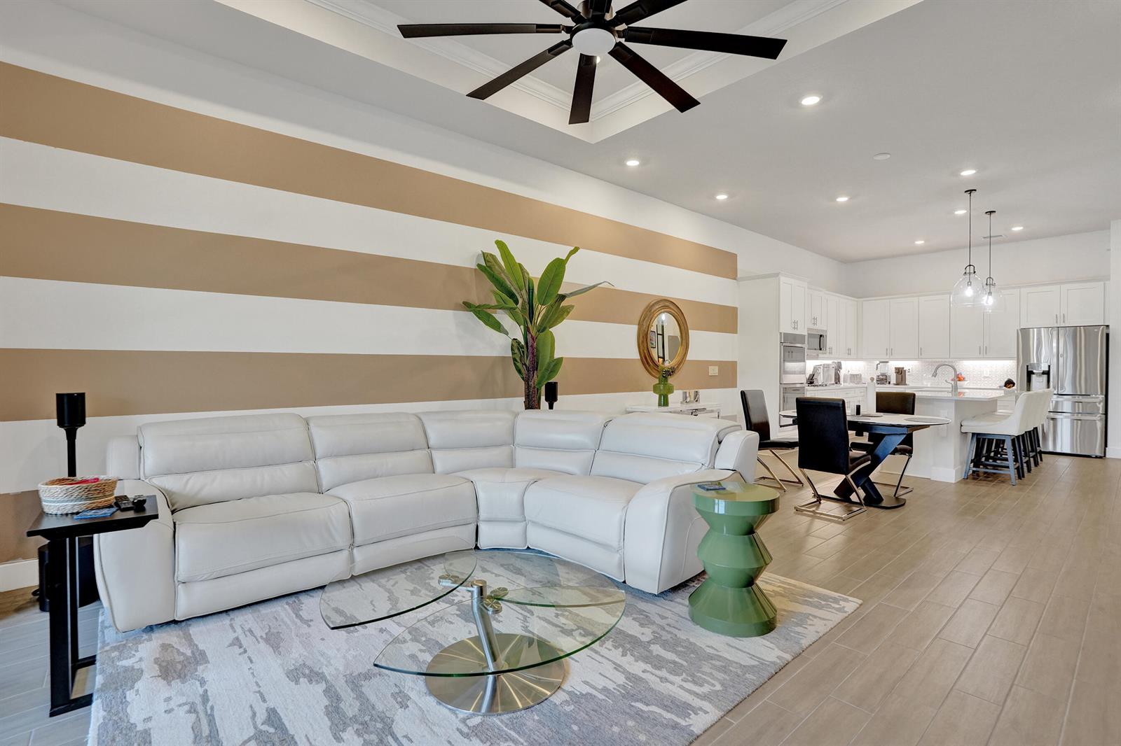 A living room with a white sectional sofa, striped wall, and an open-concept kitchen — 8334 W Blue Spring Drive # 8334, Parkland FL 33067, PARKLAND, FL