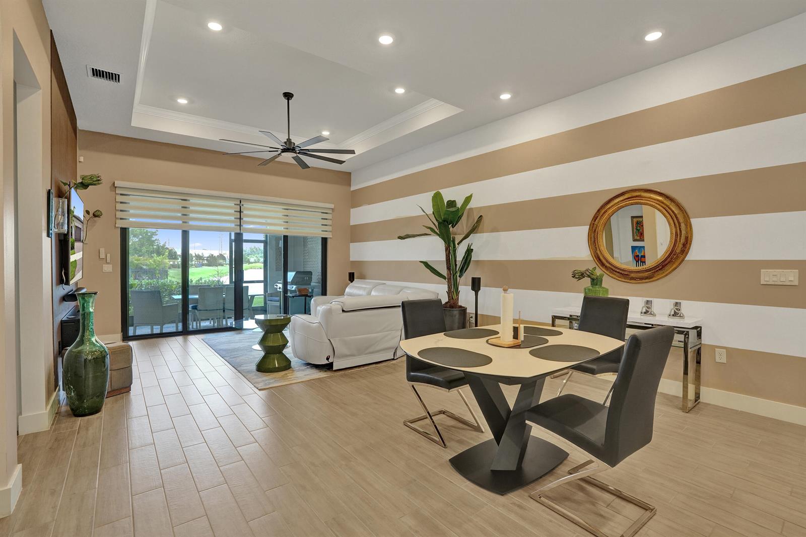 A dining and living area features striped walls, tile flooring, a ceiling fan, and patio access — 8334 W Blue Spring Drive # 8334, Parkland FL 33067, PARKLAND, FL